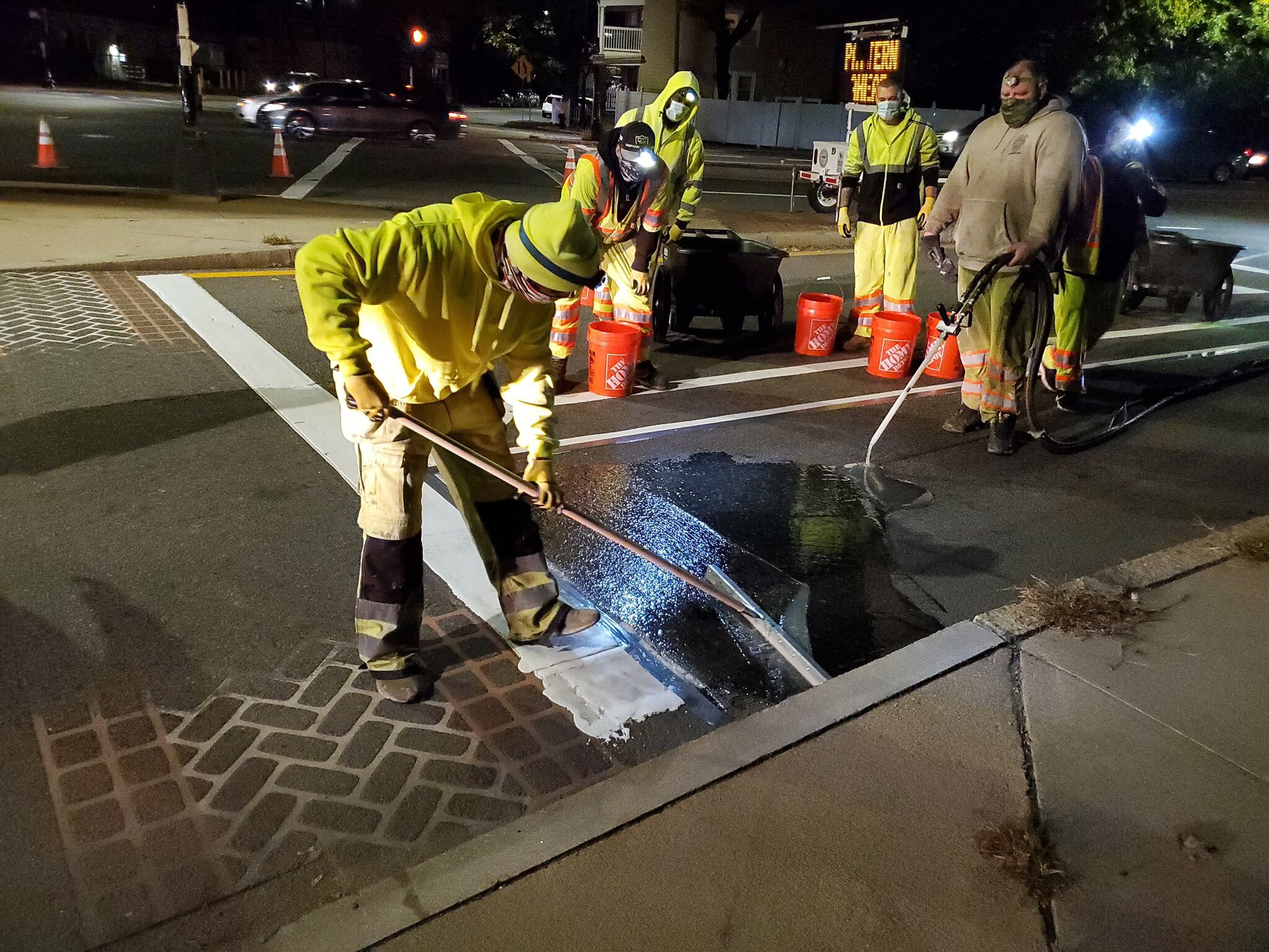Six men dressed in high visibility clothing work during the night cleaning the new bike lanes on American Legion to lay down to green color