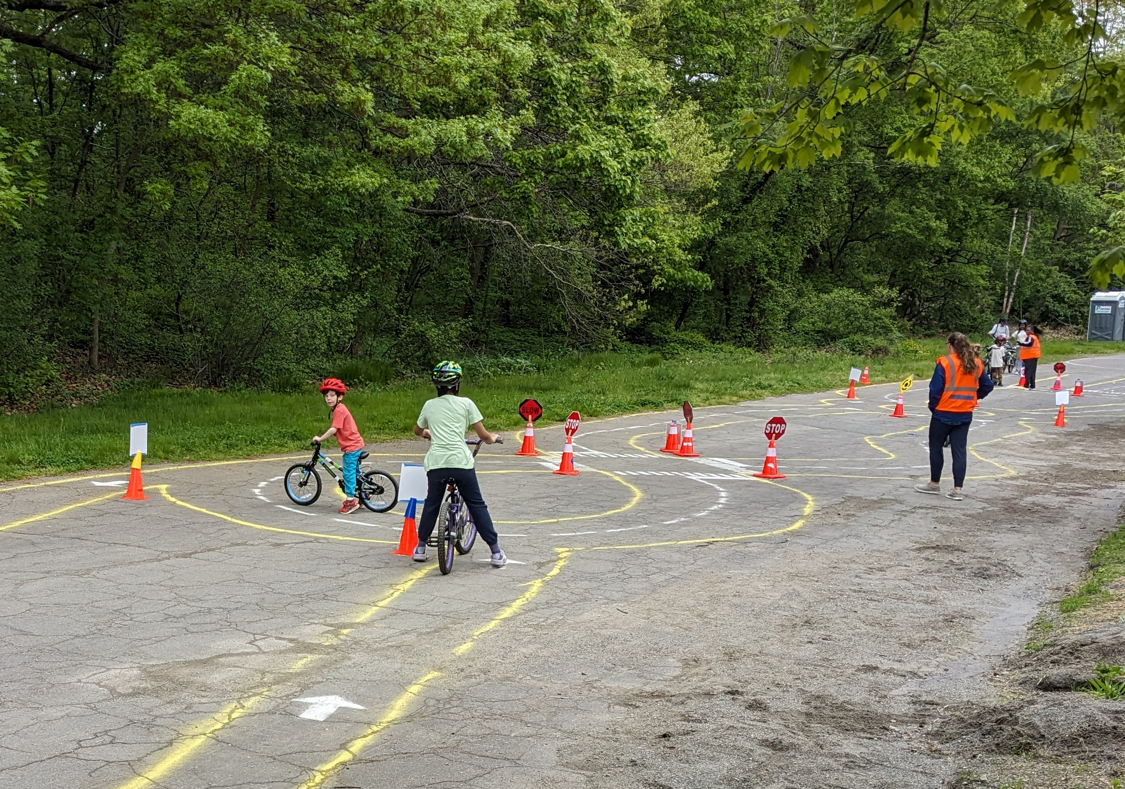 A photo of two children on bikes on a temporary traffic garden made of spray chalk on asphalt on closed street.