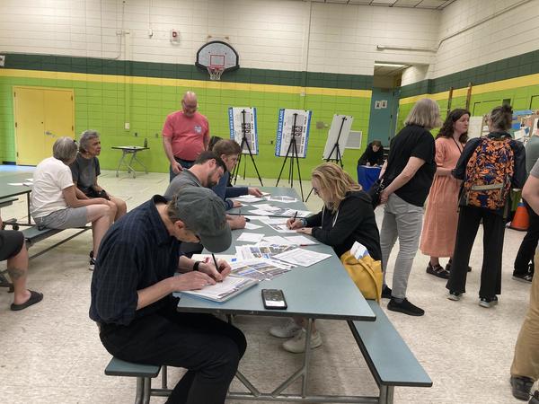 Photo of people sitting at a table writing on comment cards