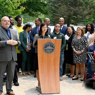 Mayor Wu stands behind a City of Boston podium surrounded by community members and City leaders.